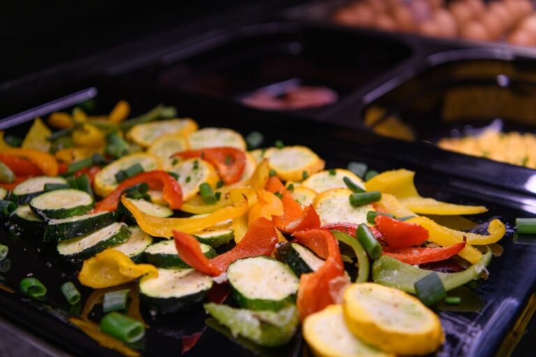 Eine farbenfrohe Mischung aus geschnittenen Zucchini, Paprika und Frühlingszwiebeln ziert ein schwarzes Tablett und erinnert an eine Gourmet-Präsentation im Hotel Bodenmais.