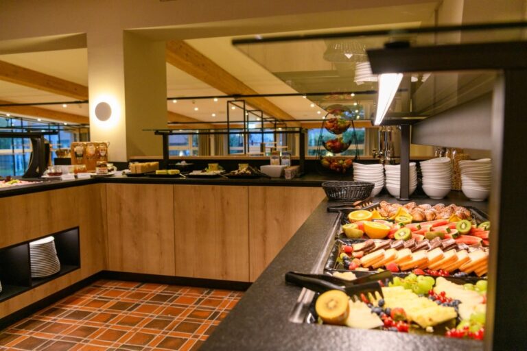 Erleben Sie ein köstliches Buffet im Hotel Bodenmais mit verschiedenen Früchten, Gebäck und Müsli in einem gut beleuchteten Raum mit charmantem Holzdekor.