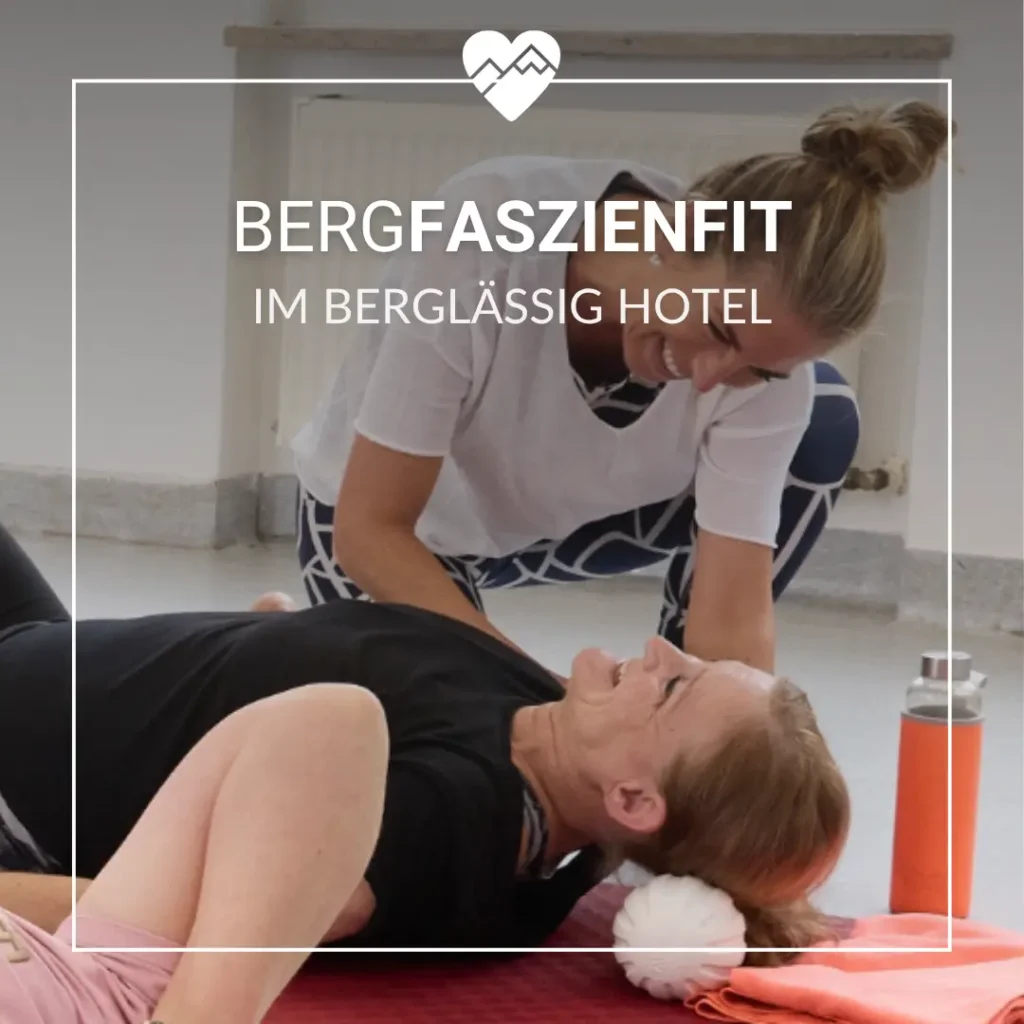 Eine Frau hilft einer anderen Frau beim Dehnen auf einer Matte im Haus, beide l&auml;cheln w&auml;hrend einer Fitness-Session.